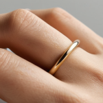 **

`A minimalist gold ring, simple band style, on a hand with neutral skin tone. Soft, diffused lighting. Emphasize elegance and understated beauty.  Focus on the ring's texture and shine.  Background is blurred and soft.`

**